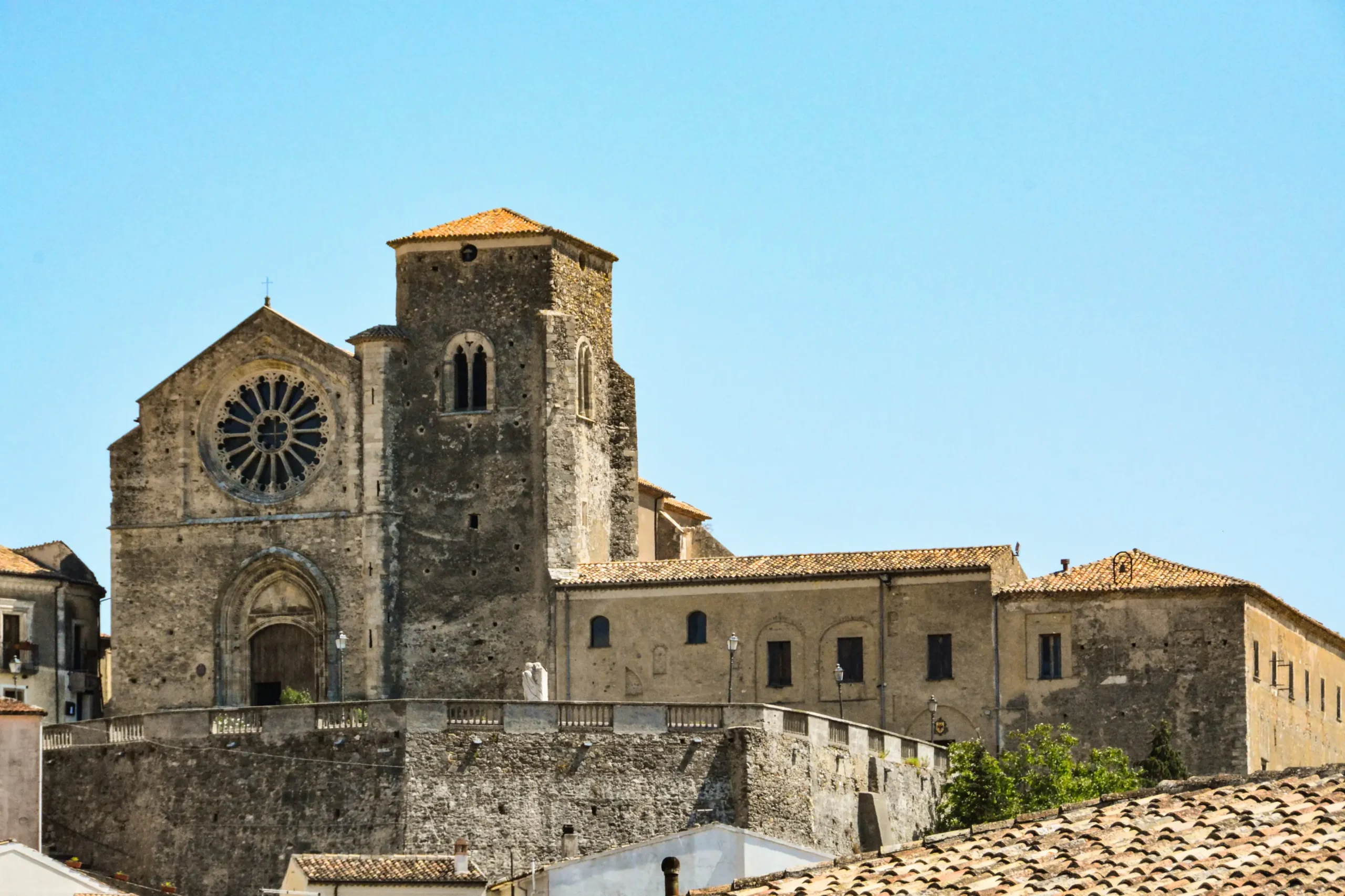 The facade of the Church of Santa Maria della Consolazione in Altomonte, featuring a large central rose window and a bell tower, ideal for weddings and historical visits.
