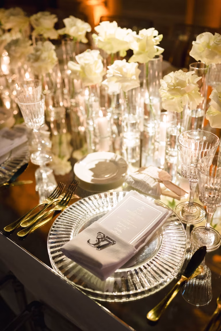 Dettaglio di mise en place elegante con fiori bianchi e candele